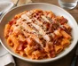 Rigatoni i kremet tomatsaus med grillet kylling, sprøstekt bacon og revet parmesan