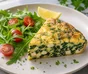Spinat- og fetafrittata i stykker med ruccola, cherrytomater og kruspersille ved siden av